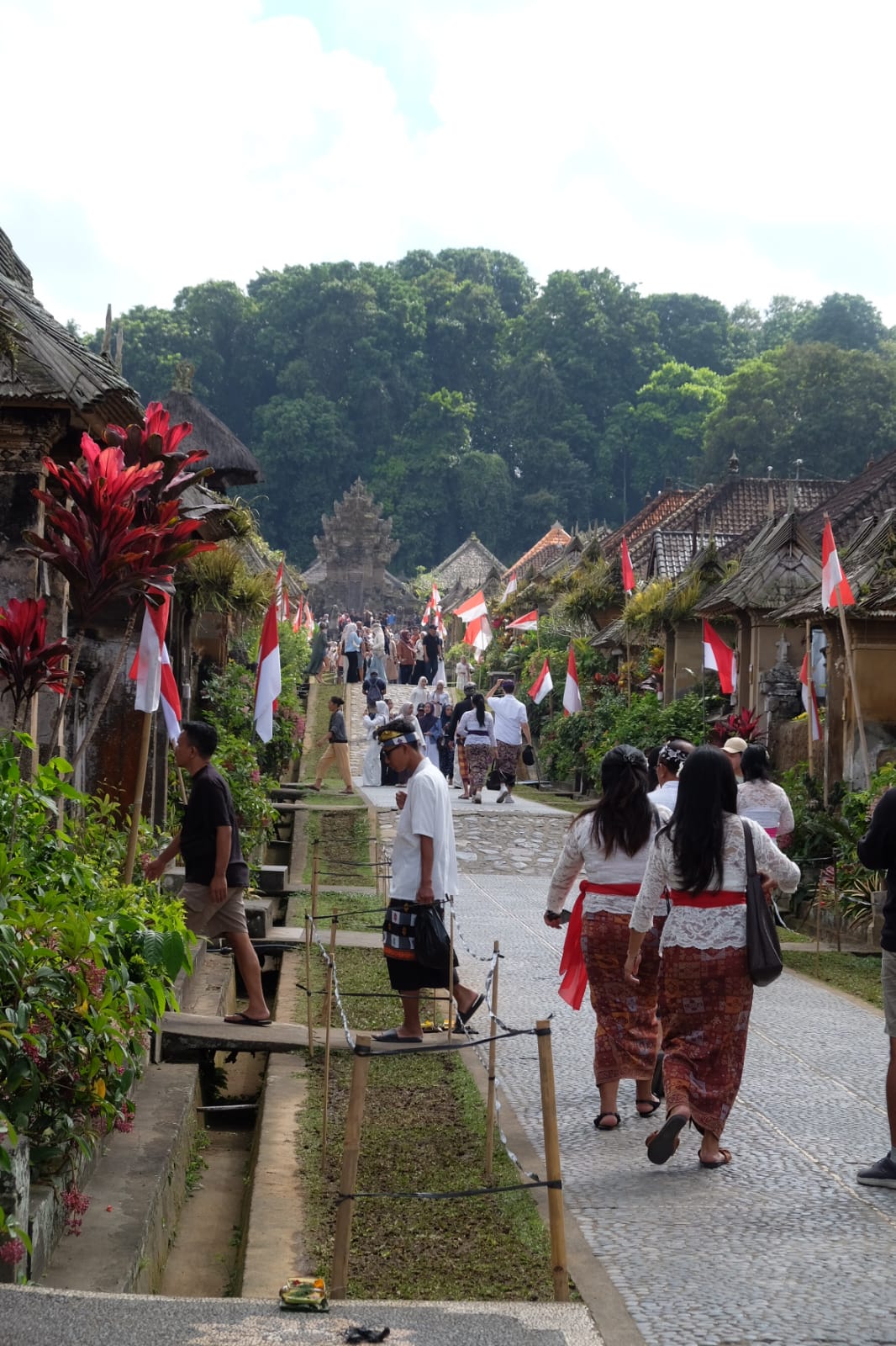 Visitors walking through the traditional stone-paved street of Penglipuran Village in Bali